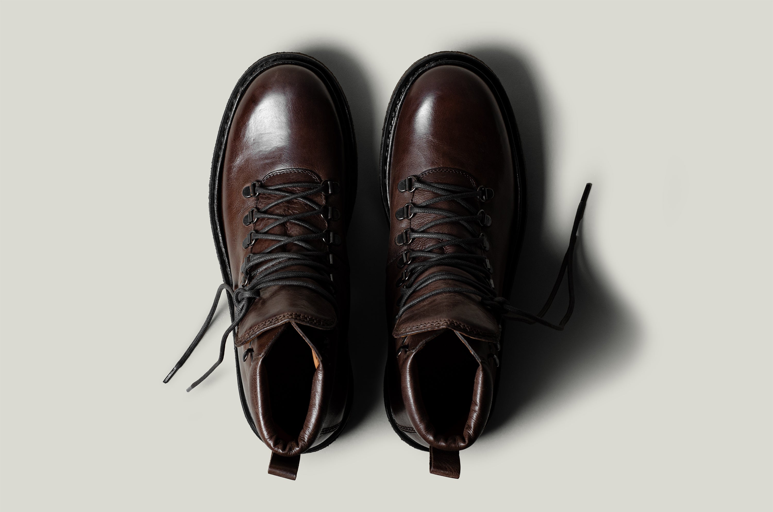 Brown leather hike boots on light grey background.
