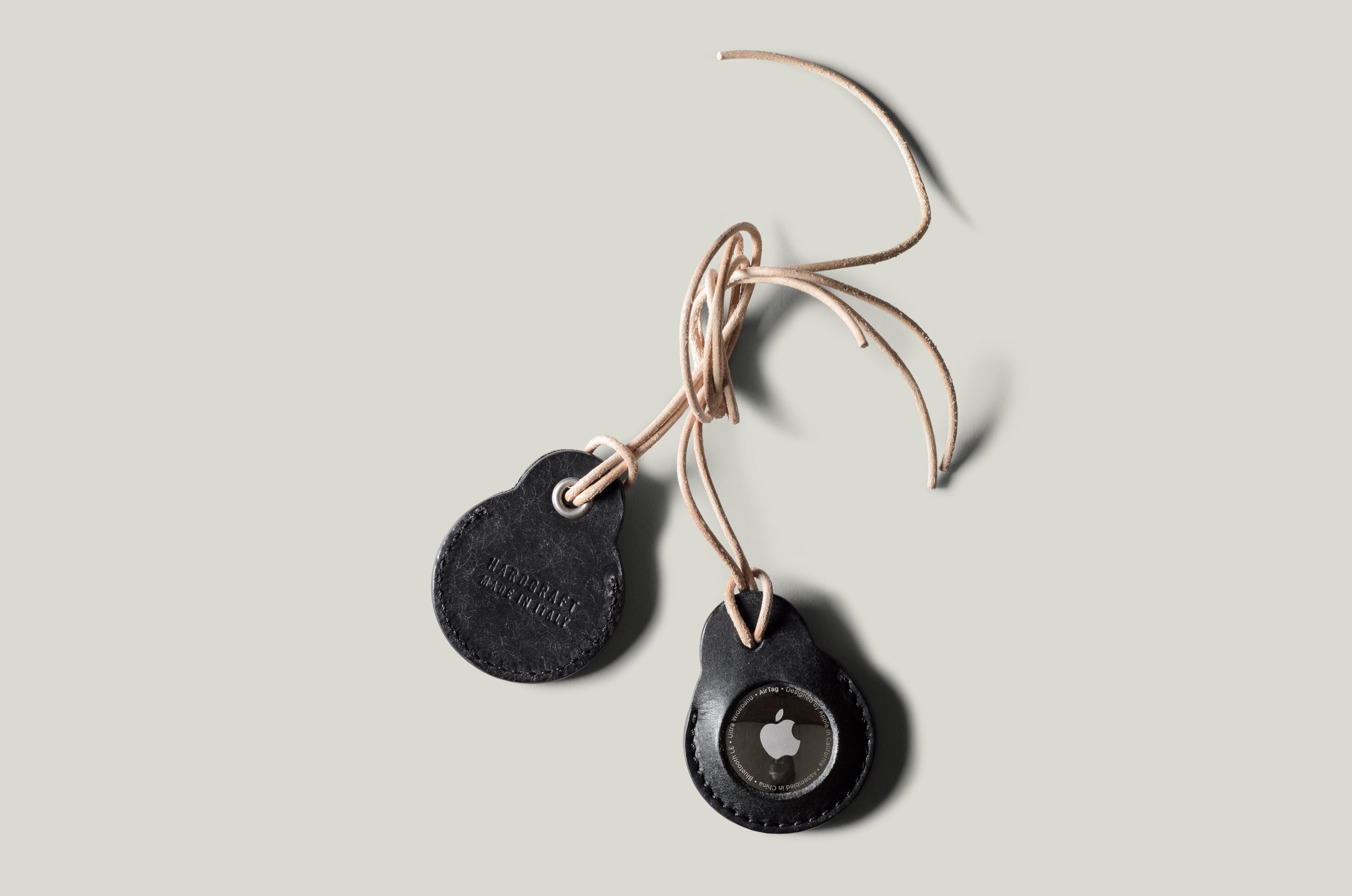 A pair of black leather Apple airtag holders on light grey background