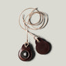 A pair of dark brown apple airtag holders on a light grey background