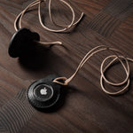 A pair of black leather Apple airtag holders on wood background