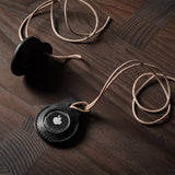 A pair of black leather Apple airtag holders on wood background