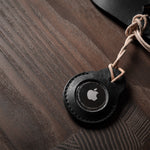 A pair of black leather Apple airtag holders on wood background