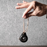 A pair of black leather Apple airtag holders held by a hand