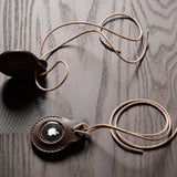 A pair of dark brown apple airtag holders on a wood background