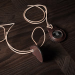 A pair of dark brown apple airtag holders on a wood background