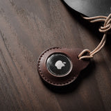 A pair of dark brown apple airtag holders on a wood background