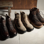 Set of brown and beige boots on a concrete floor with a wooden bench in the background.