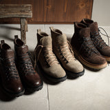 Set of brown and beige boots on a concrete floor with a wooden bench in the background.
