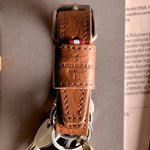 Brown leather key belt on busy background.