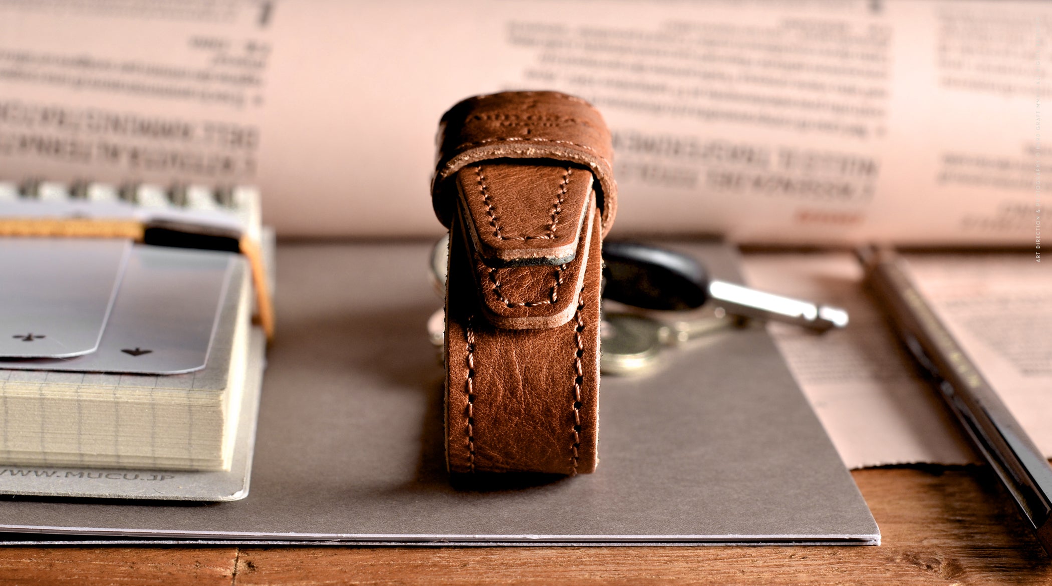 Brown leather key belt on busy background.