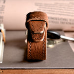 Brown leather key belt on busy background.