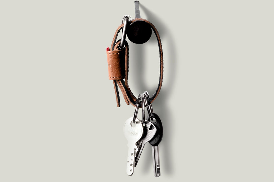 Brown leather key belt on light background.