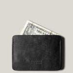 Black leather card case with a dollar bill on a gray background