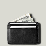 Black card case with money and cards on a light gray background