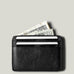 Black card case with money and cards on a light gray background
