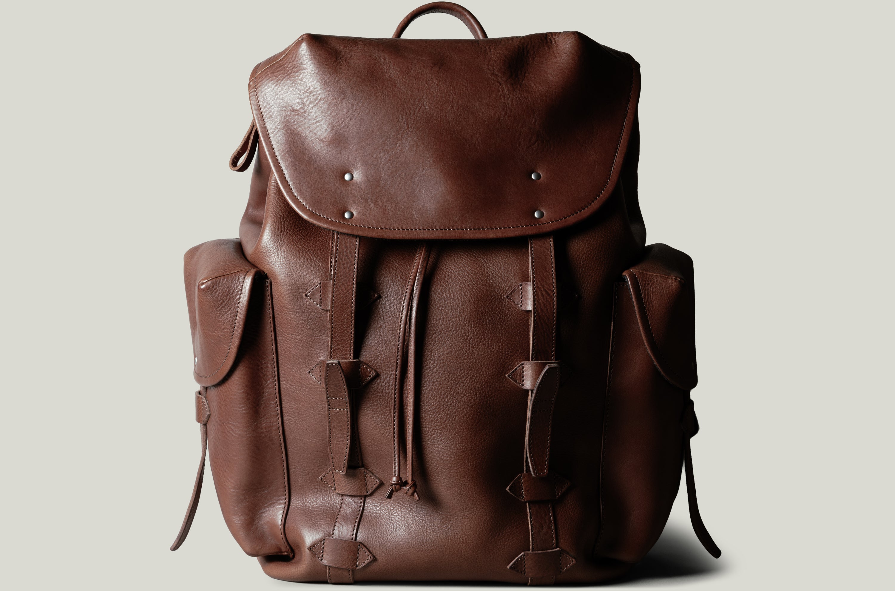 Brown leather backpack on a light gray background