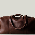 Brown leather duffel bag on a light beige background