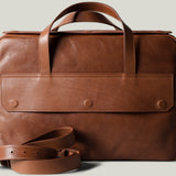 Brown leather briefcase with strap on a light gray background
