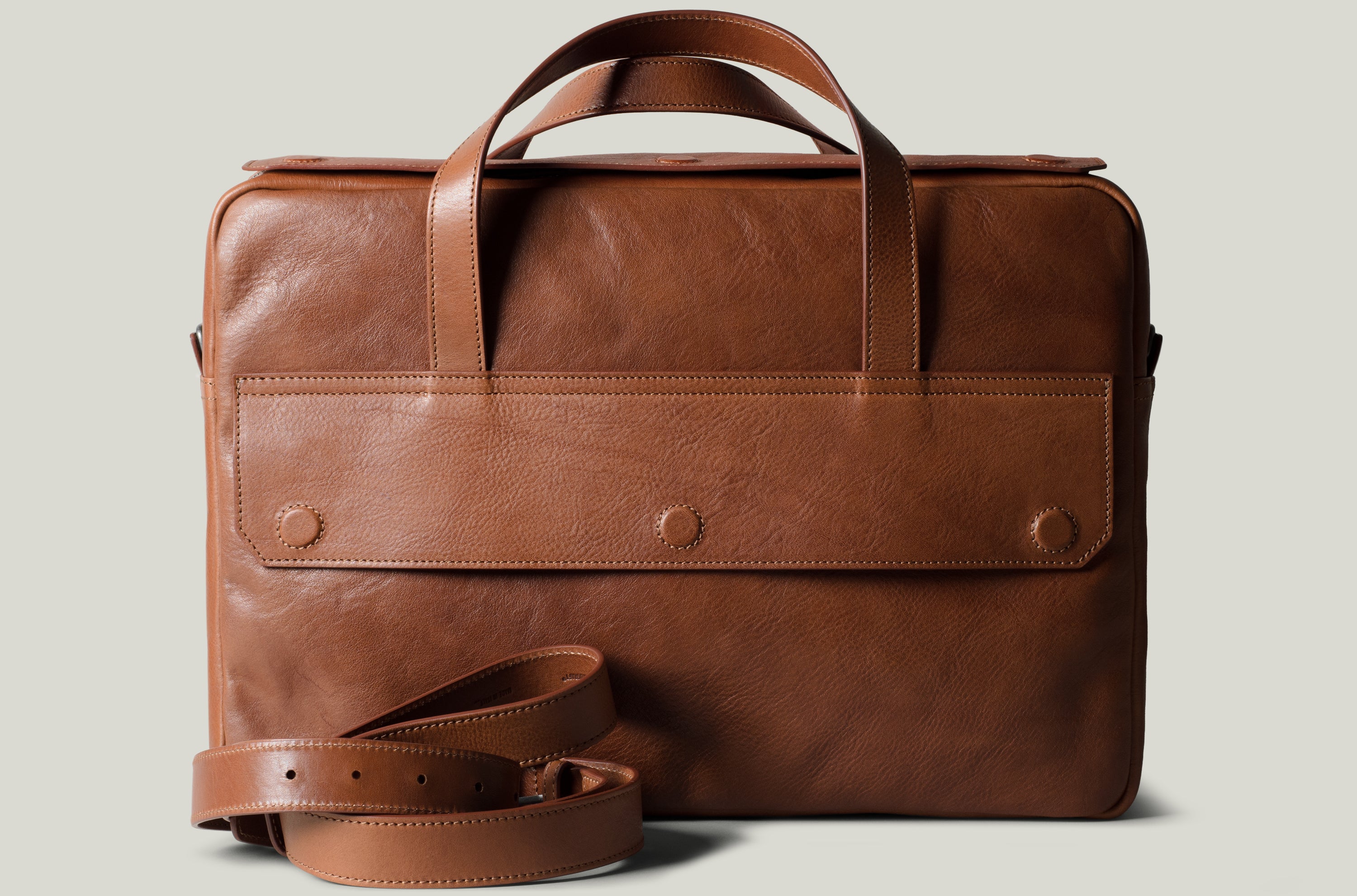 Brown leather briefcase with strap on a light gray background