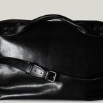 Black leather bag with a strap on a light gray background
