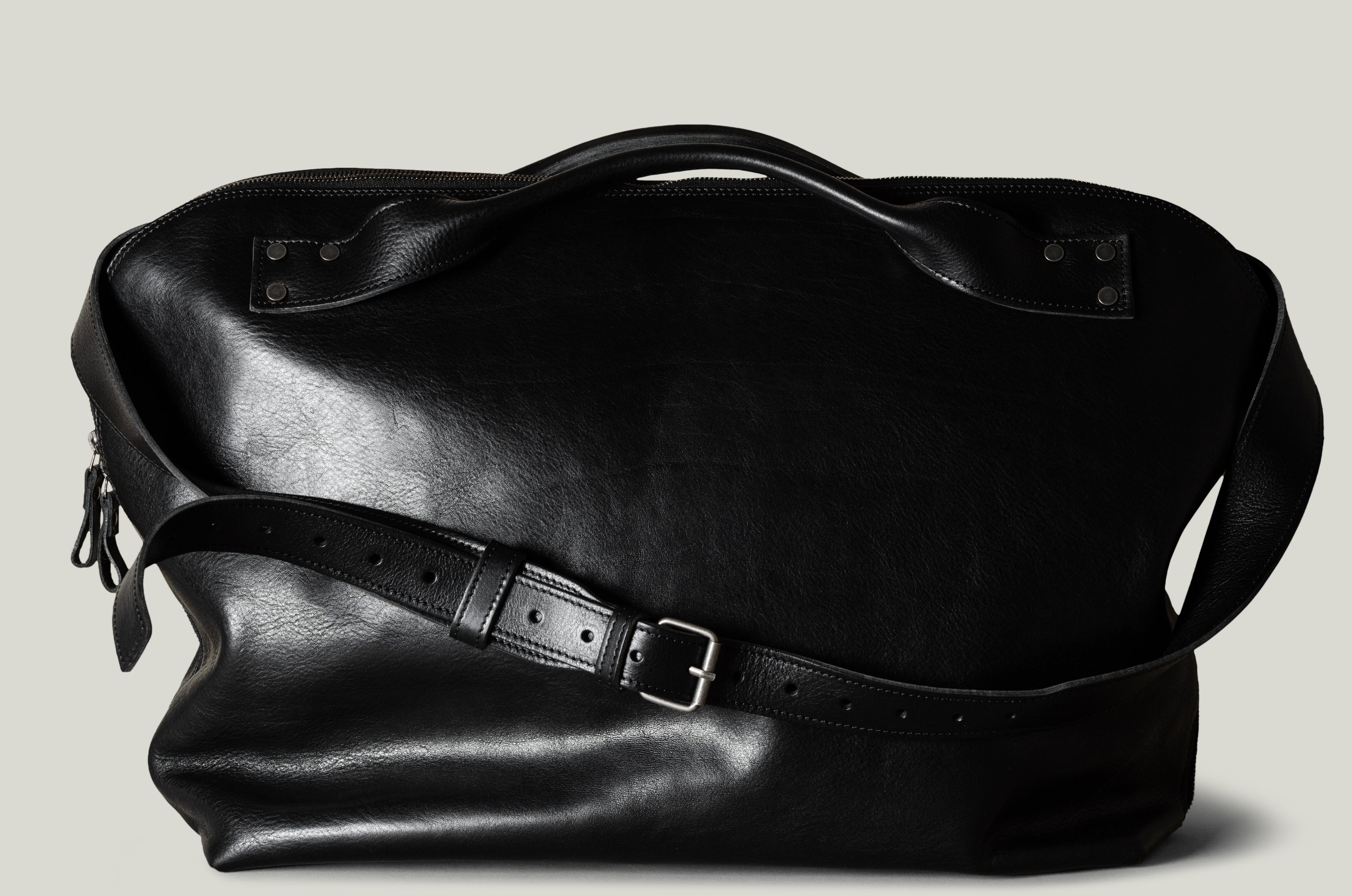 Black leather bag with a strap on a light gray background