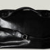 Black leather bag with a strap on a light gray background