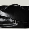 Black leather bag with a strap on a light gray background