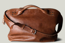 Brown leather duffel bag on a light gray background