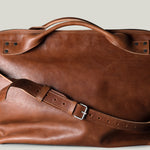 Brown leather duffel bag on a light gray background