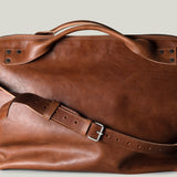 Brown leather duffel bag on a light gray background