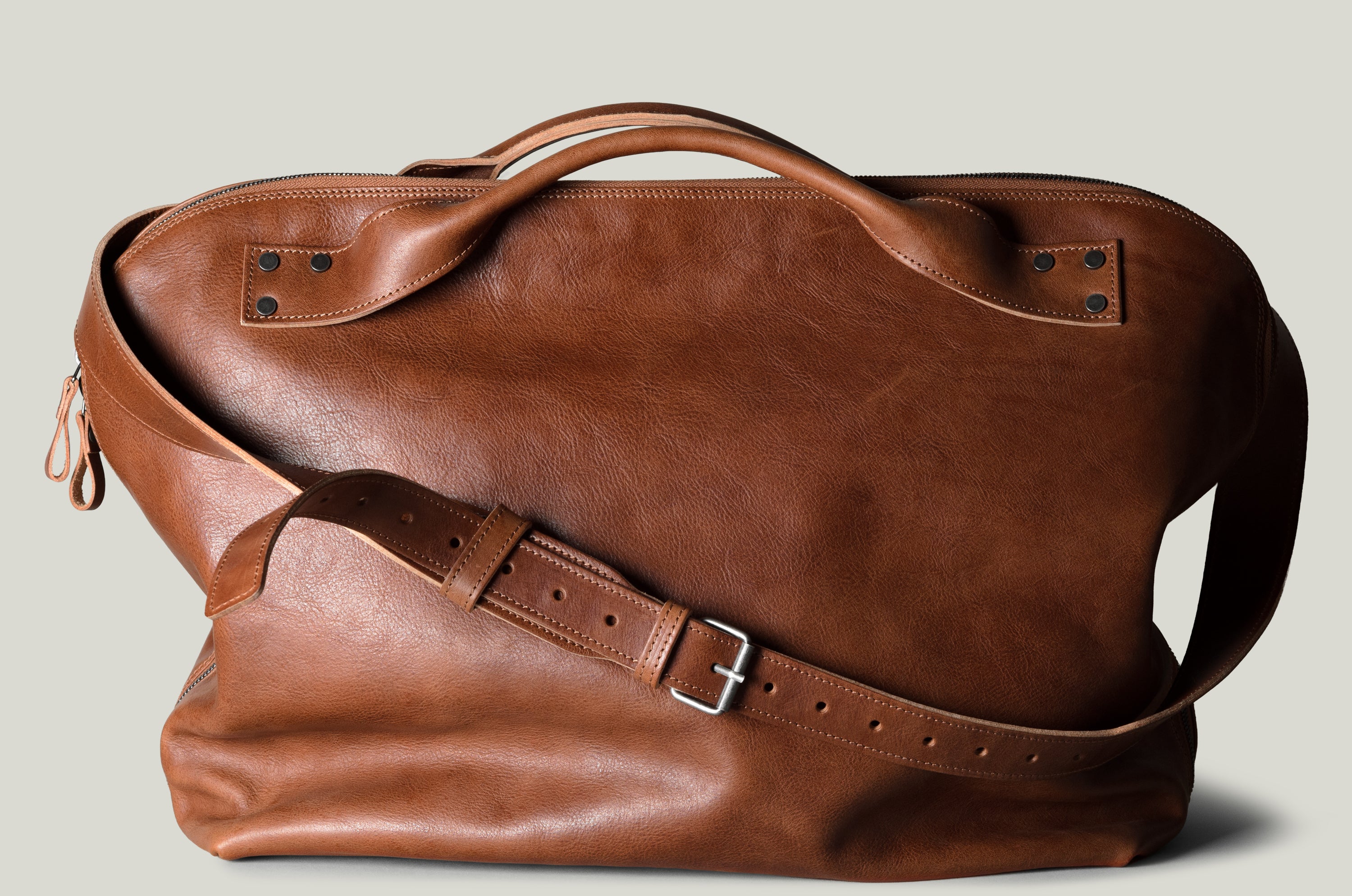 Brown leather duffel bag on a light gray background