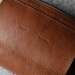 Brown leather bag with visible hardgraft brand name on a textured surface
