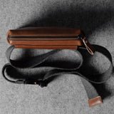 Brown leather bag with a strap on a gray textured background