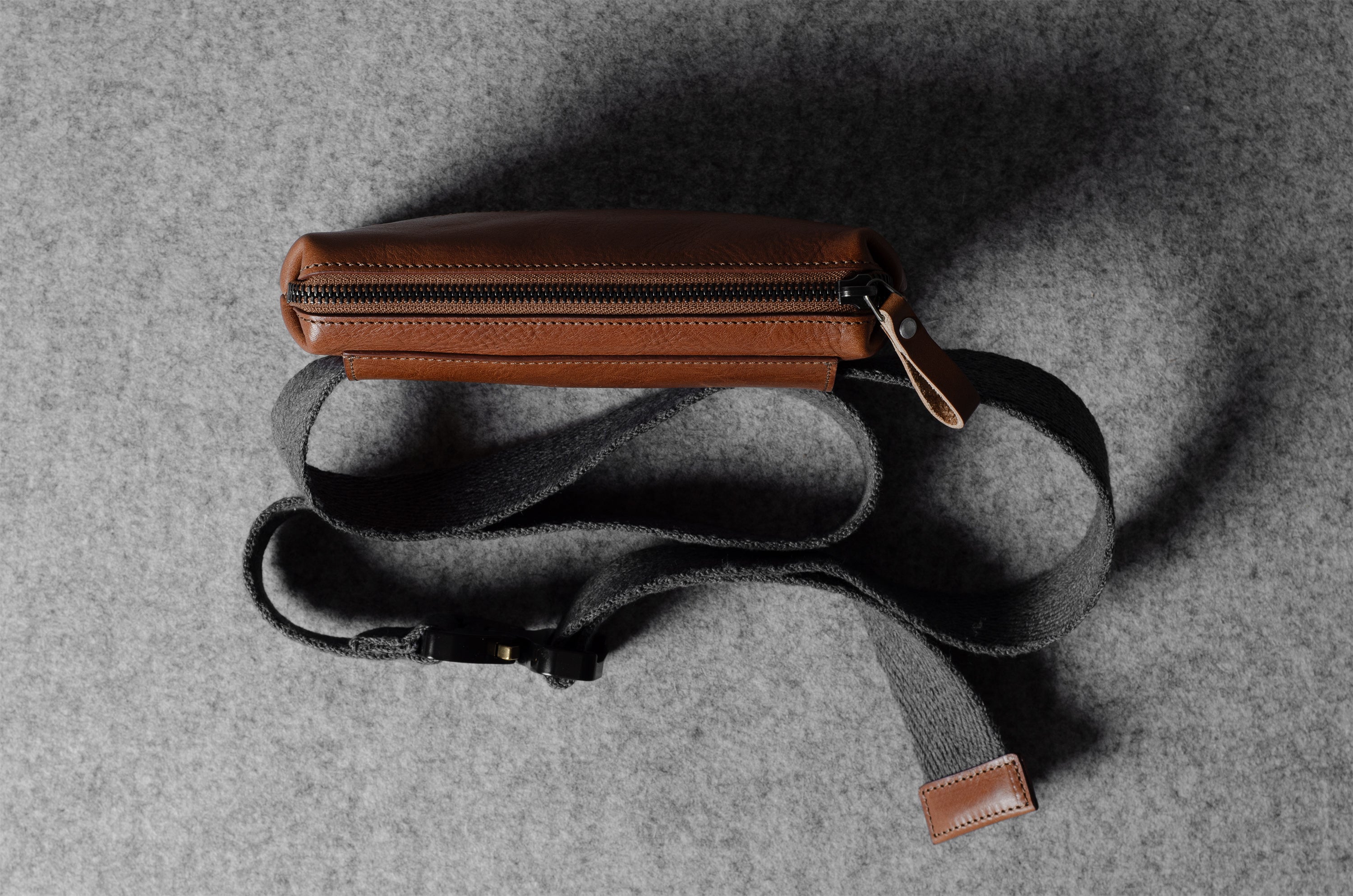 Brown leather bag with a strap on a gray textured background