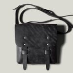 Black leather bag with strap on a light gray background