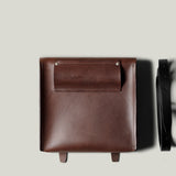 Brown leather bag with a strap on a light gray background
