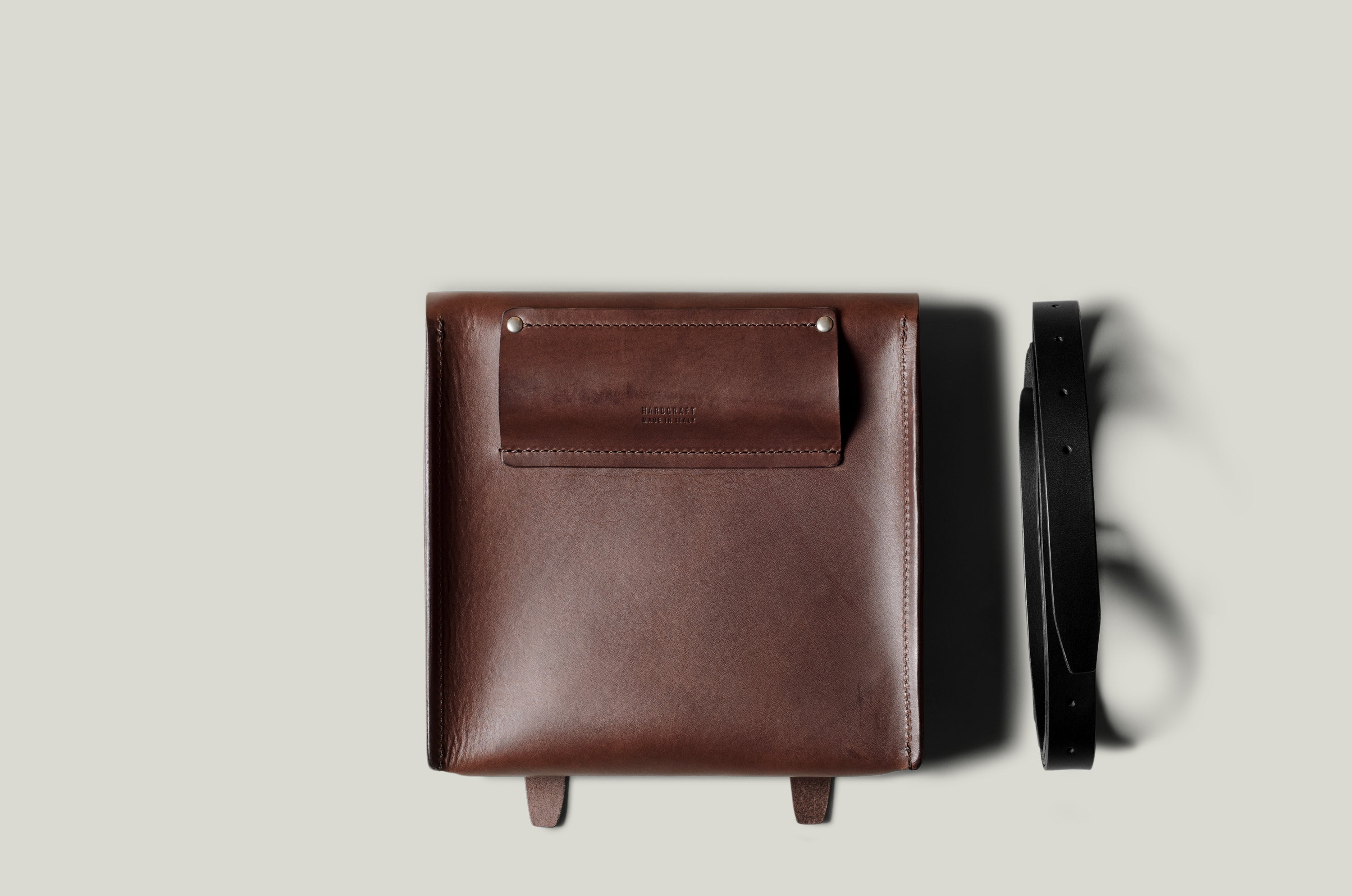 Brown leather bag with a strap on a light gray background