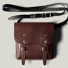Brown leather bag with a black strap on a light gray background