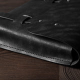 Close-up of a black leather bag on a wooden surface