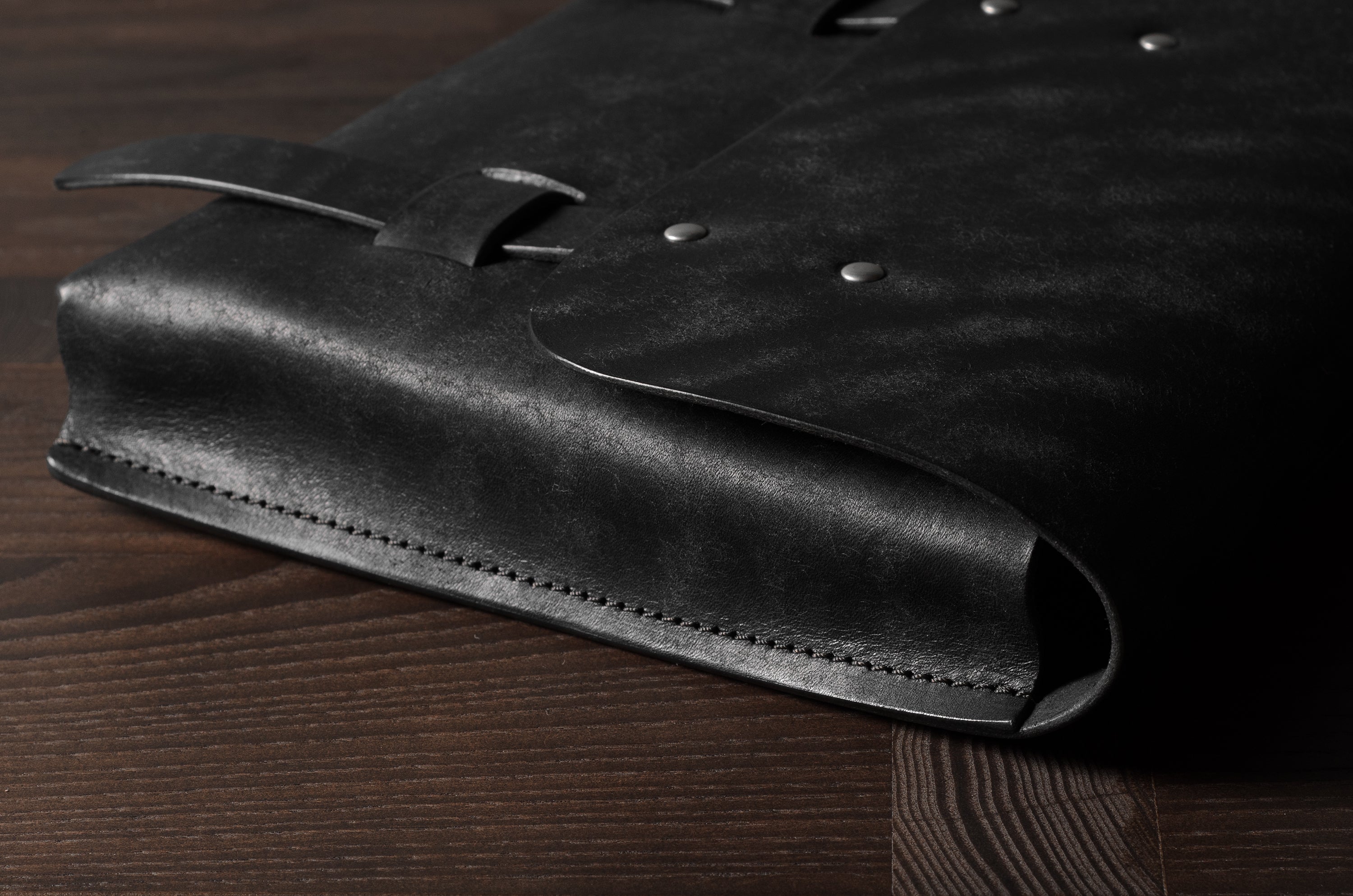 Close-up of a black leather bag on a wooden surface