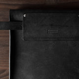 Black leather bag with a brand logo on a wooden surface