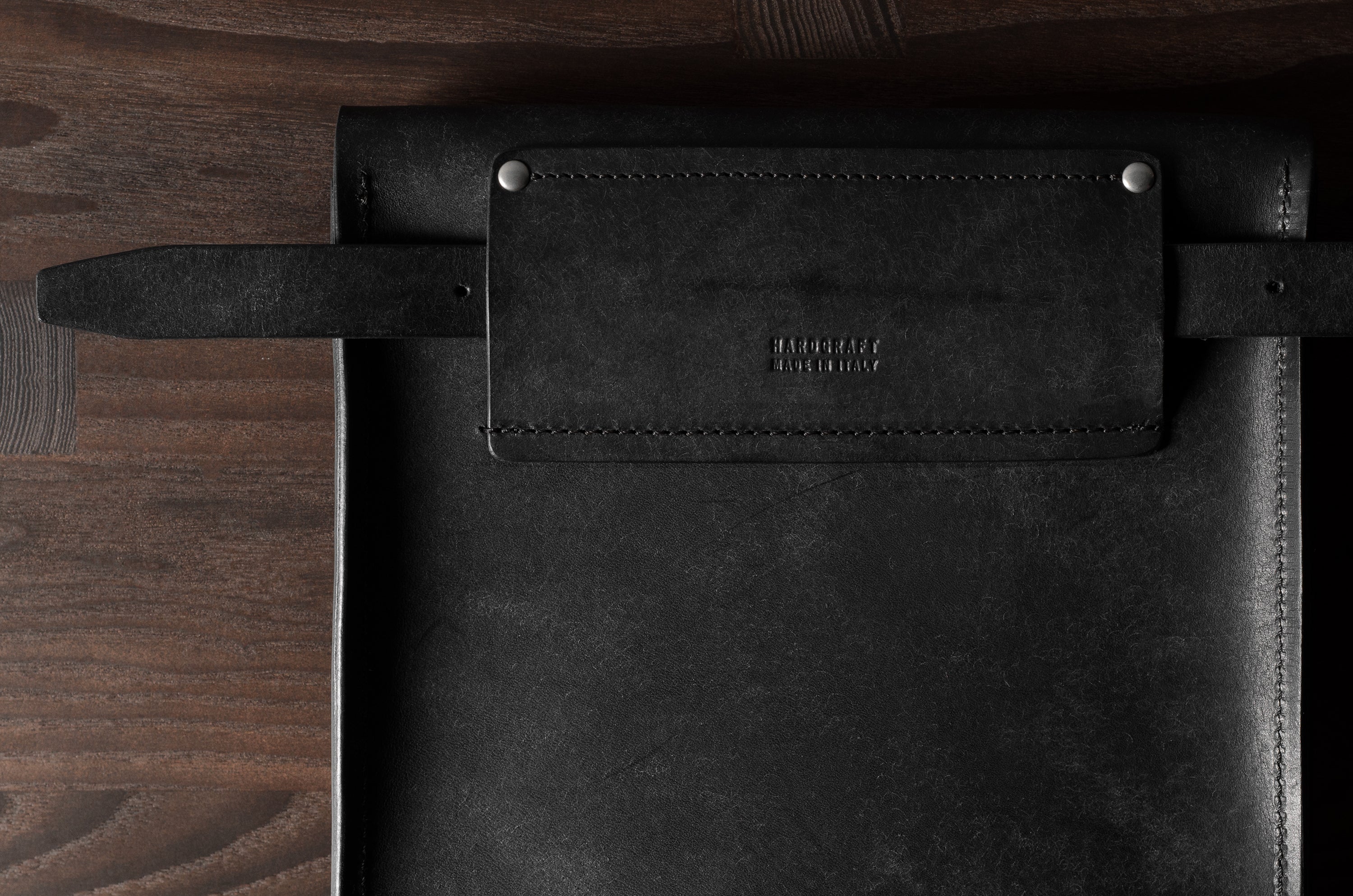 Black leather bag with a brand logo on a wooden surface