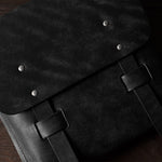 Close-up of a black leather bag with metal rivets on a wooden surface
