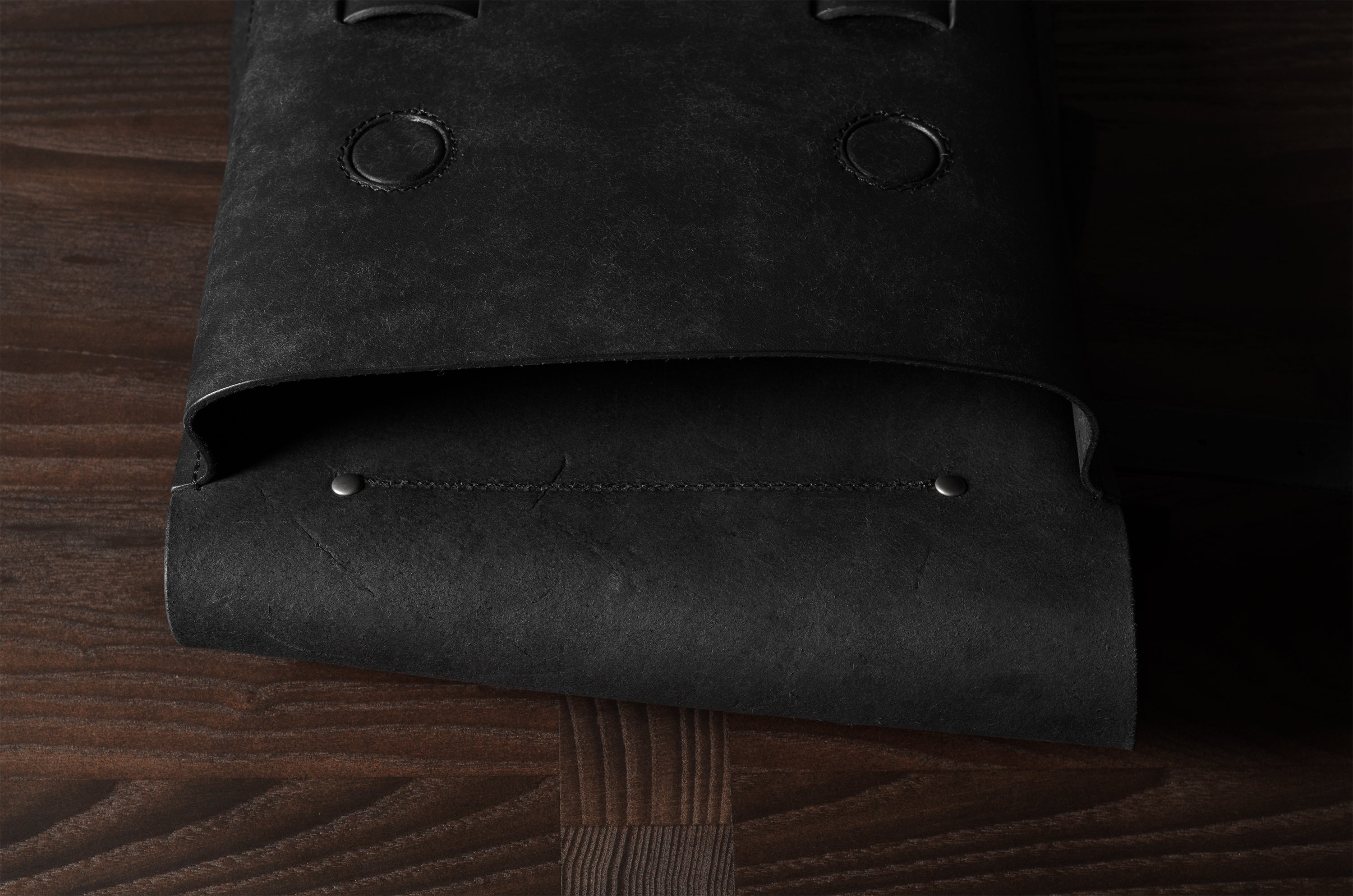 Open flap of black bag on a wooden surface