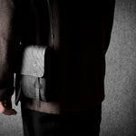 Person holding a black  leather bag against a gray background