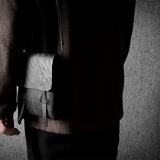 Person holding a black  leather bag against a gray background