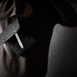 Person wearing a dark sweater with a black bag on a gray background