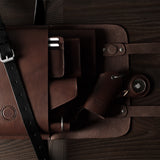 Brown leather bag with a strap on a wooden surface