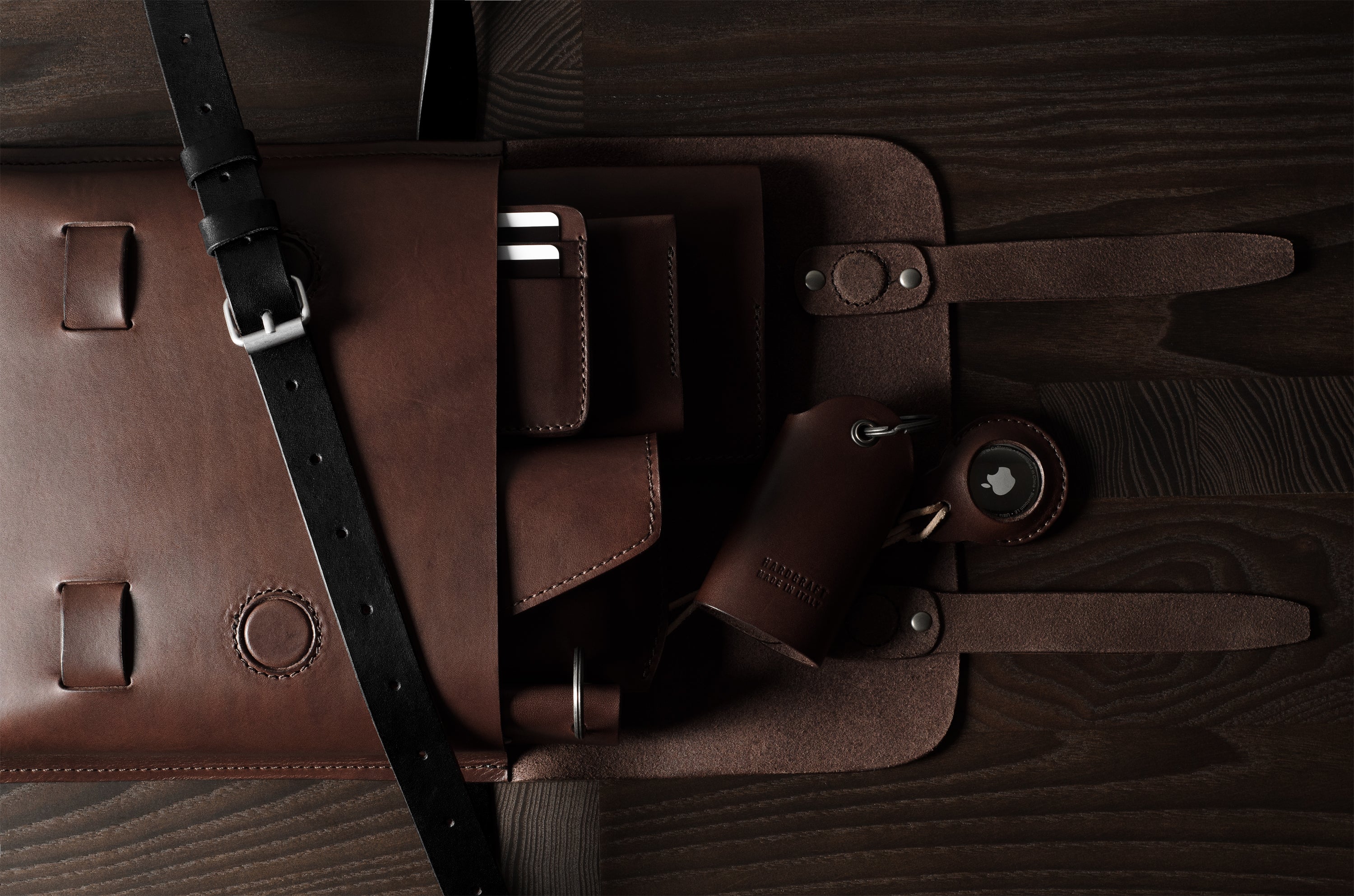 Brown leather bag with a strap on a wooden surface