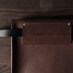 Brown leather bag with a strap on a wooden surface
